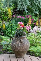 An old urn planted with geraniums on decking