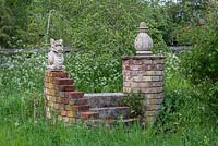 Engulfed in cow parsley, a small brick and statue folly.