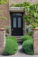 A lavender and olive tree lined path leads to the front door, overhung by a white wisteria.