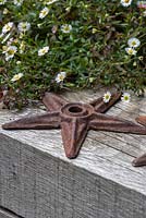 An old iron starfish rests on a timber beam.
