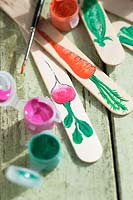 Painting ice lolly sticks to make plant labels for vegetables 
