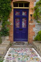 A colourful mosaic path leading to a blue front door