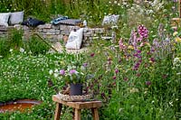 Springwatch Garden - Hampton Court Flower Show 2019 - designer, Jo Thompson - stool with a vase display of cut flowers in wildlife friendly garden