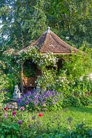 View to octagonal summerhouse covered with rambling roses. Rosa 'Climbing CÃ©cile BrÃ¼nner'