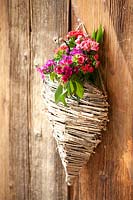Dianthus displayed in straw vase hanging on the wall