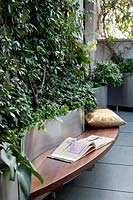 Built-in wooden bench seat around curving silver steel planters