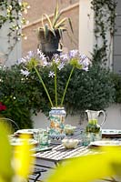 Vase of cut flowers on outdoor dining table set for lunch