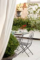 Dining area on roof terrace with large planters and classic urn