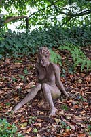 Statue of Daphne sitting in the woodland. 