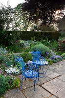 Blue painted metal table and chairs on terrace in garden. 