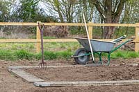 Wheelbarrow, fork, rake and wooden boards, tools and equipment for making a new kitchen garden