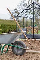 Wheelbarrow and rake for ground preparation in new kitchen garden