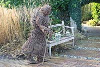 Woven sculpture of woman walking with stick