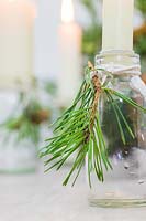 Close up detail of small glass bottles adorned with cut pine foliage