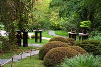 Summer Japanese garden with clipped evergreen round shaped Buxus topiary and bonsai trees collection on the wooden â€“ stoned stands.