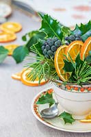 Teacup filled with Holly, Ivy berries, Pine foliage and dried orange slices