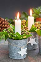 Table decoration featuring candles in miniature galvanised buckets filed with Ivy berries and Bay leaves
