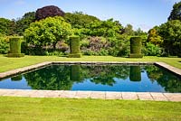 Reflective pool and clipped Yew columns - Taxus baccata - in the Silent Garden at Scampston Hall Walled Garden, North Yorkshire, UK. 
