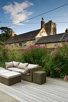 Centranthus ruber behind rattan furniture on wooden decking - garden next to pub