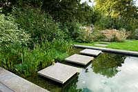 Paving slabs as stepping stones over modern pond - natural swimming pool