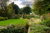 Raised borders and central lawn in modern country garden