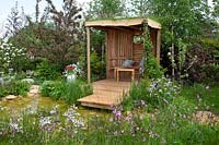 The garden shelter, next to the dew pond, surrounded by wildflowers in 'Garden Inspiration: The Dew Pond' at RHS Malvern Spring Festival 2018