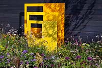 Dark clad wall with yellow steel sculptural panels, and pings of bright colours throughout in 'Urban Oasis' at RHS Malvern Spring Festival 2018