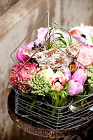 Metal basket with mixed buttercups, sweet peas and roses