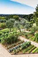 A kitchen garden with long beds, overlooking countryside with trees