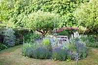 Summer garden with central sculpture in bed of Lavender, Salvia turkestanica, Eryngium, Dianthus, and Rosa 'American Pillar' 