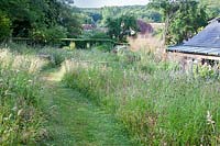 Grass pathway through wildflower meadow, countryside beyond