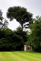 View up striped lawn to The Temple with mature trees behind