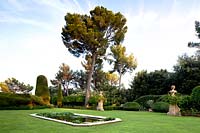 Formal pond set in a lawn, topiary and trees beyond