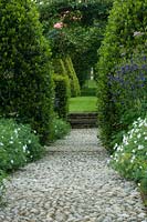 Cobbled pathway through formal country garden with steps up to lawn area