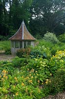 Summerhouse in bog garden of Primula and Hosta 