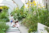 children play on the terrace with container grown perennial grasses and herbaceous plants