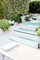 Modern terrace garden with swimming pool and sun loungers. 