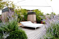 Large sun bed stands on terrace surrounded by Agapanthus, Perovskia atriplicifolia and Rosmarinum prostratrum