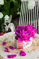 Peonies displayed in ceramic dish on table in garden.  