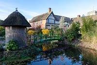 A Monet bridge crosses a pond and leads to a summerhouse with thatched roof