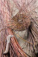 Piece of basketry on cut bundles of stems with cutting tool nearby