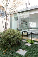 Terrace garden with view to house through glass doors. 
