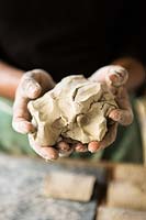 Raw clay being worked in beteen hands