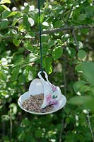 Bird feeder made from china tea cup and saucer hanging in tree 