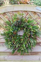 Red themed winter wreath hung on wooden gate