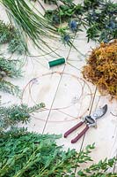 Tools and materials required to make green-themed winter wreath.