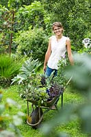 Woman with wheelbarrow full of plants 