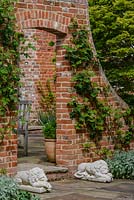 Brick wall with Rosa - Climbing Rose - 'Claire Austin' and 'Wollerton Old Hall',  brick arch entrance flanked by sleeping lion statues