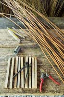 Tools ready to make a fence for borders with woven willows and chestnut stakes. 
