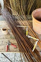 Stems of willow and tools to make woven plant cone supports. 